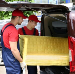 Günstig umziehen in Meiningen Günstig umziehen in Meiningen: Umzugshelfer laden ein gelbes Sofa in einen Transporter