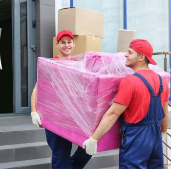 Umzug in Meiningen Zwei Umzugshelfer tragen ein in Folie gepacktes Möbelstück – Umzug in Meiningen